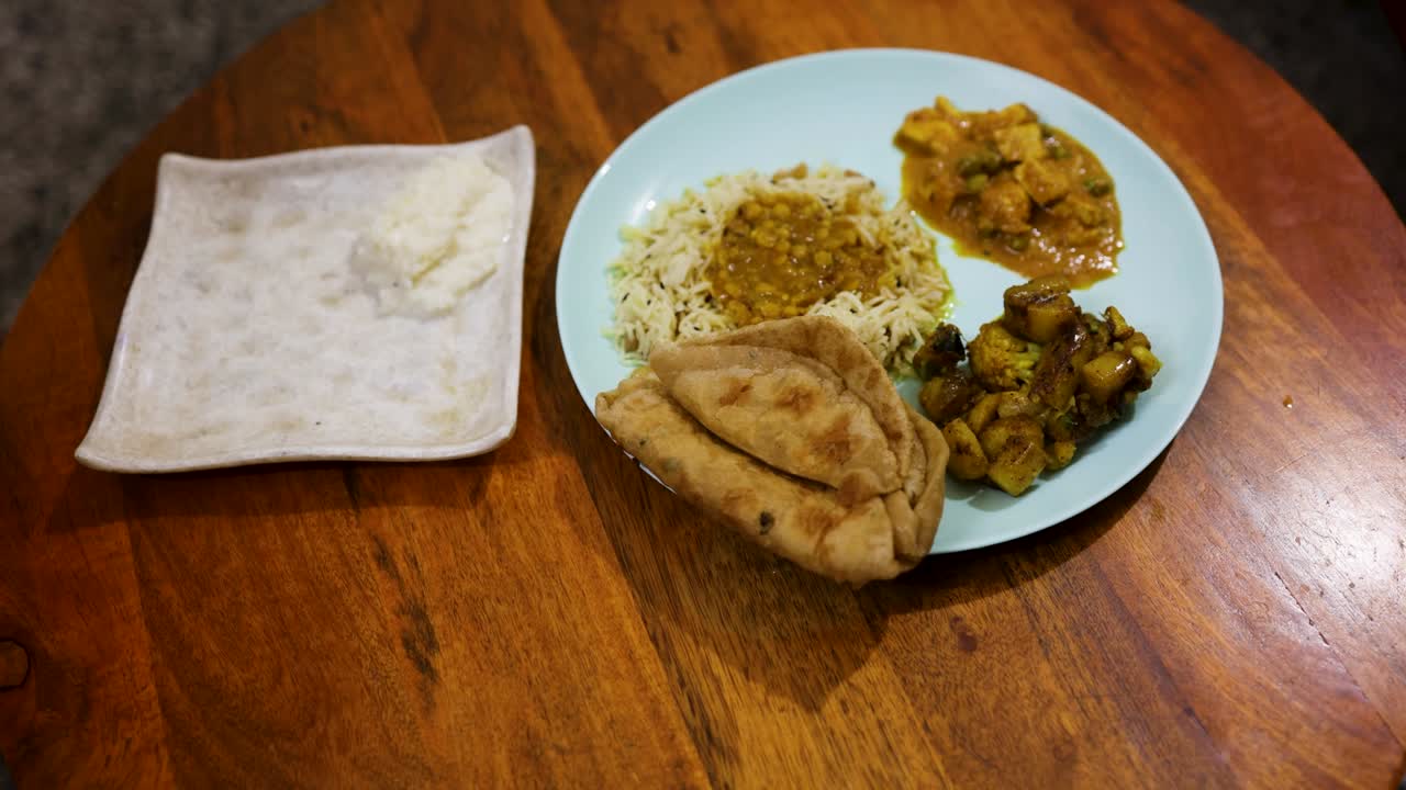 timelaspe of Top view of homemade Indian meal with roti rice dal and gulab jamun