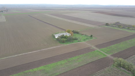 White-farmhouse-drone-aerial-in-brown-meadows-during-cold-winter-morning