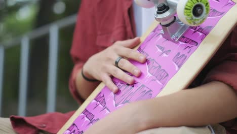 young boy sitting with his skateboard in his arms and listening to music