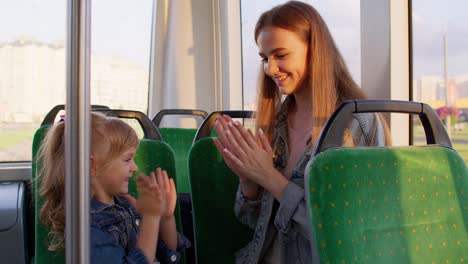 a happy mother and daughter play a game on a bus