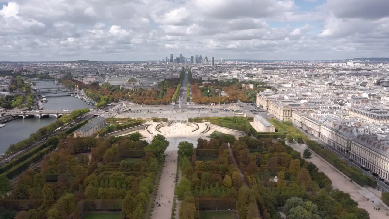 A breathtaking aerial drone view over Paris captures the Tuileries Garden, the Seine River, and the historic city skyline stretching into the horizon