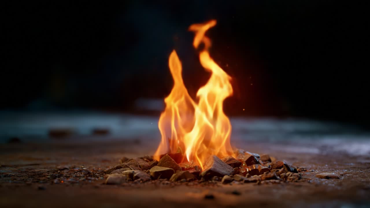 A mesmerizing display of flames dancing upon a bed of stones, emitting sparks and warmth, showcasing the raw beauty and power of fire in a darkened environment