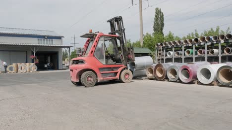 forklift driver loads rolls of steel sheet. industrial warehouse with rolls of steel sheet