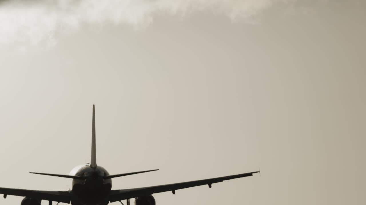 공항에 착륙하기 위해 석양 아래에서 매우 느린 속도로 머리 위를 날아가는 비행기