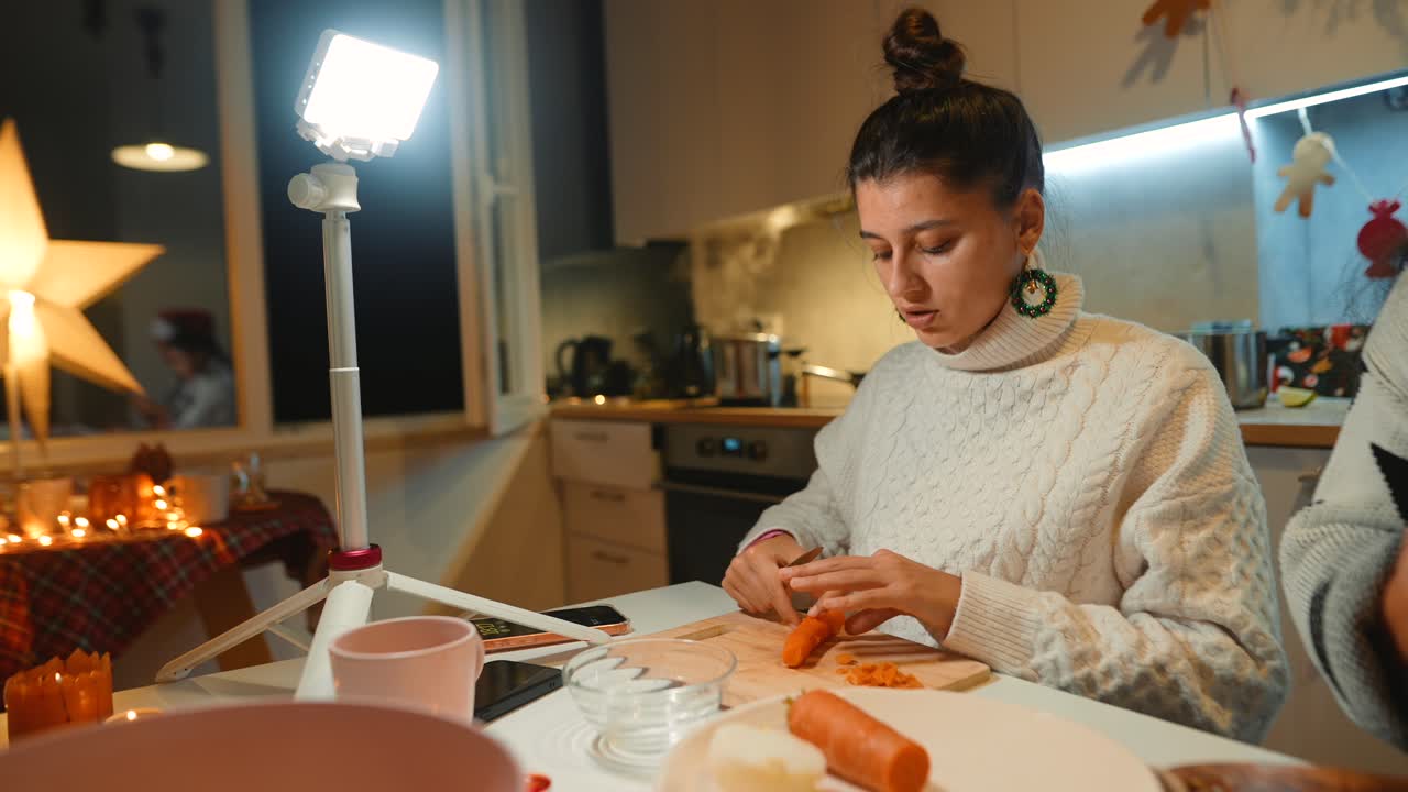 A woman cutting a carrot in the kitchen