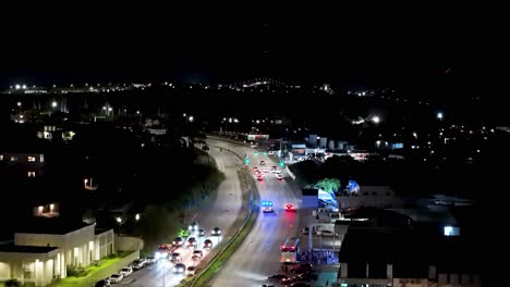 Las-Luces-Azules-Intermitentes-De-La-Ambulancia-Se-Reflejan-En-Los-Edificios-De-La-Ciudad-Mientras-Conduce-A-Emergencias,-Inclinación-Aérea-Hacia-Arriba