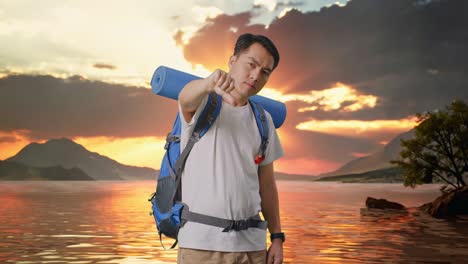 asian male hiker with mountaineering backpack showing thumbs down gesture at a lake