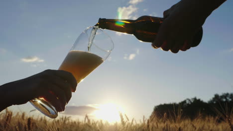 vierta la cerveza en un vaso contra un fondo borroso del campo de cebada