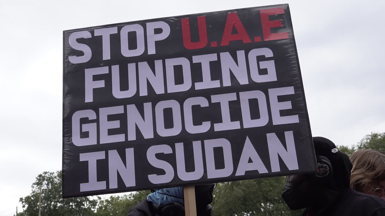 A black, red and white placard is held up that reads, “Stop U.A.E funding genocide in Sudan” during a Hands Off Sudan protest at Marble Arch.