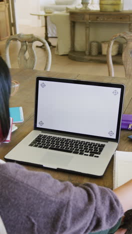 vertical video of biracial teenager girl using laptop with copy space, in slow motion
