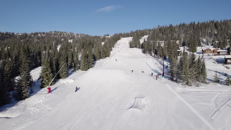 4K-Luftdrohne-Eines-Snowboarders,-Der-An-Einem-Sonnigen-Wintertag-In-Norwegen-Einen-360-Grad-Trick-Im-Vergnügungspark-Eines-Skigebiets-Springt