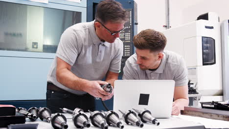 engineer showing apprentice how use cad software on laptop