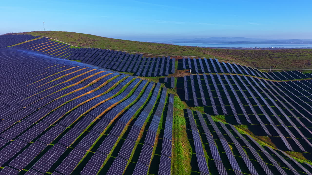 Levende solcelleparklandskab indfanger essensen af vedvarende energi i et smukt grønt bakket landskab under en klar blå himmel