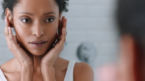 portrait beautiful african american woman looking in mirror at perfect skin enjoying natural complexion winking confidently getting ready at home