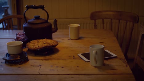 coffee cup, digital tablet, food and teapot on table