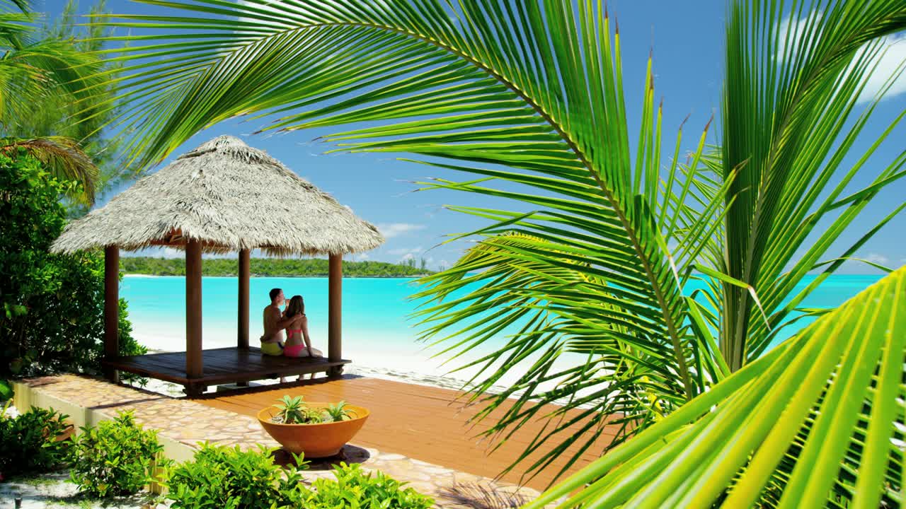 una pareja caucásica sentada en una cabaña de tiki del caribe