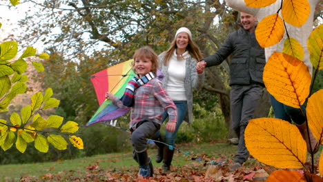 animation of fall leaves falling over happy caucasian family in autumn park