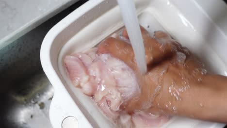 lavando el pecho de pollo en un cuenco blanco