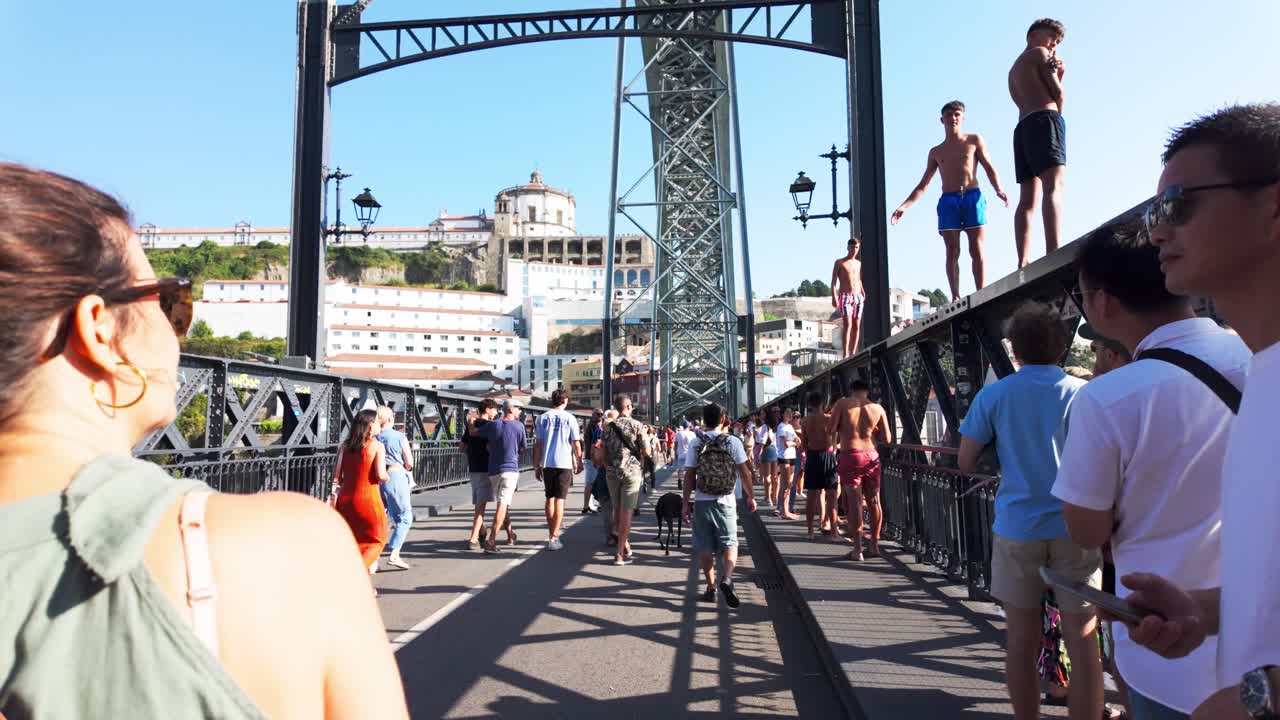 People walking on a busy Luís I Bridge in Porto, sunny day with tourists and locals