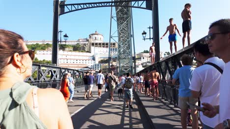people walking on a busy luís i bridge in porto, sunny day with tourists and locals