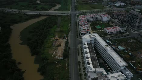 fly in over new development,wetlands and roads revealing river and city skyline view with high rise towers in early morning