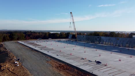 an-ascending-drone-shot-showing-off-the-full-process-of-lifting-a-concrete-panel-into-place-via-a-heavy-duty-crane