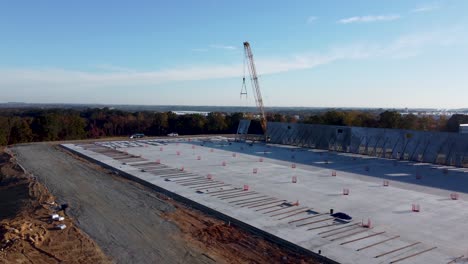 una toma de dron ascendente que muestra el proceso completo de levantar un panel de concreto en su lugar a través de una grúa de servicio pesado