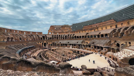 pov forward showing epic historic italian colosseum in rome during cloudy day - wide shot showing many tourist visiting landmark - largest standing amphitheatre in the world today