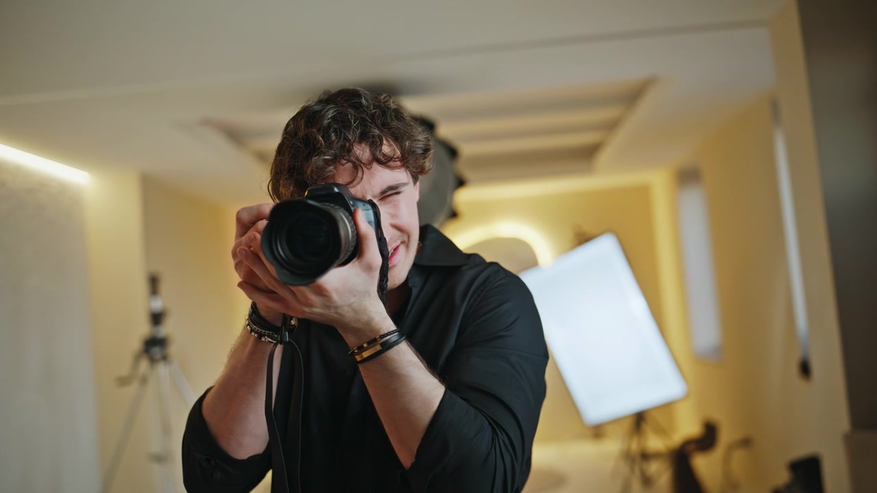 Kameramann sikter DSLR-kamera i modellstudio. Fotograf gir en hjelpende hånd.