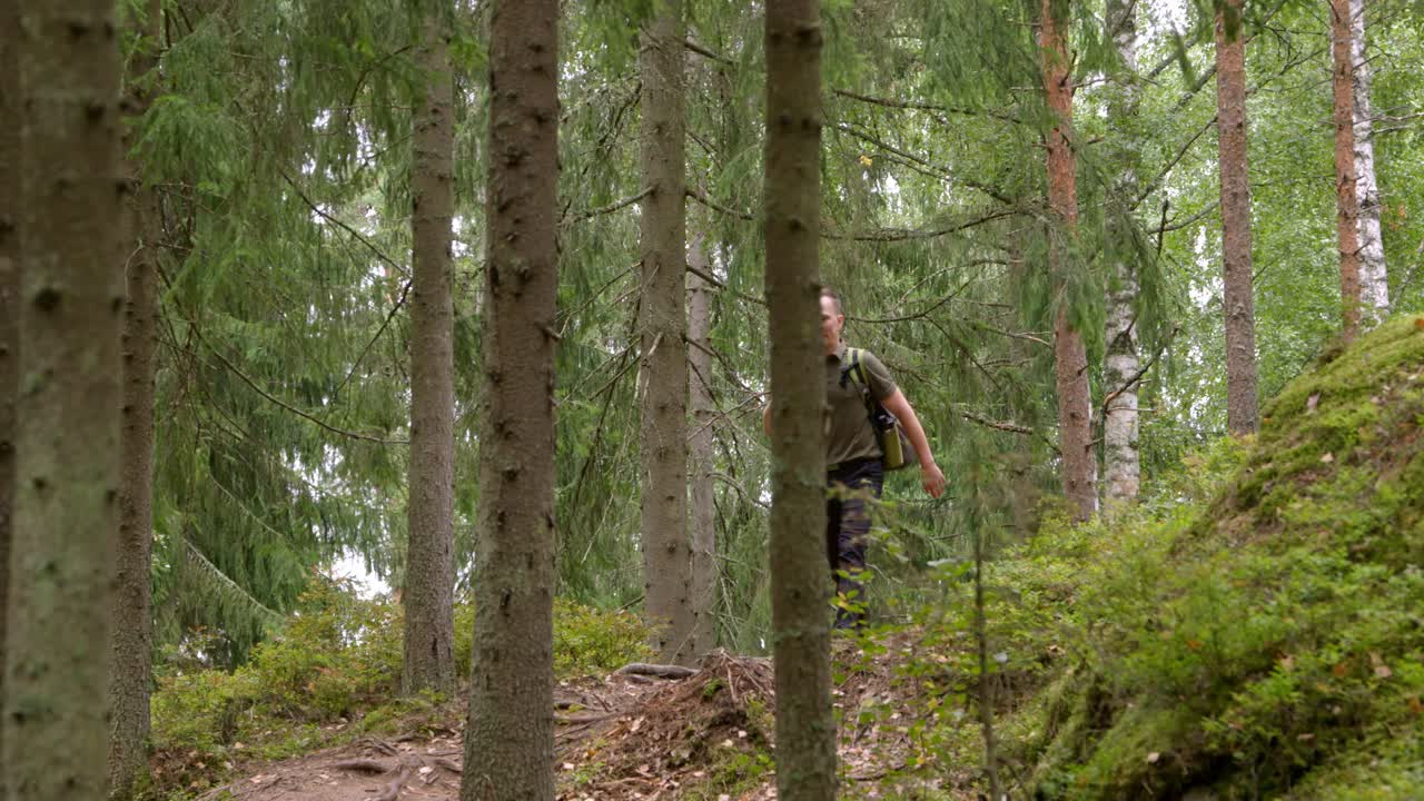 Disc golfer walking in Finnish forest to the next course