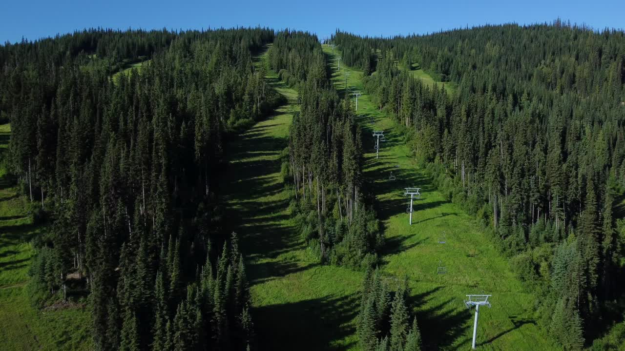 Chairlifts at ski resort surrounded by green forests in Canada