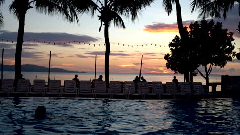 a man is swimming and diving in the pool against the sunset