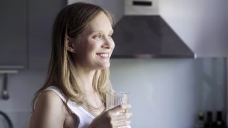 beautiful pregnant woman drinking water from glass