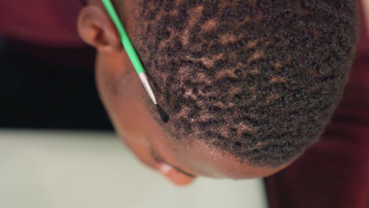 Colorazione dall'alto di capelli neri con pennello, pratica professionale di styling e applicazione di prodotti in salone su una modella studentessa seduta; l'inquadratura ravvicinata mostra il cuoio capelluto, i motivi delle onde e il movimento del pennello.