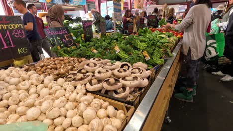 shoppers selecting vegetables at a market stall