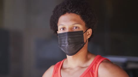 portrait of fit african american man exercising in city wearing face mask in the street
