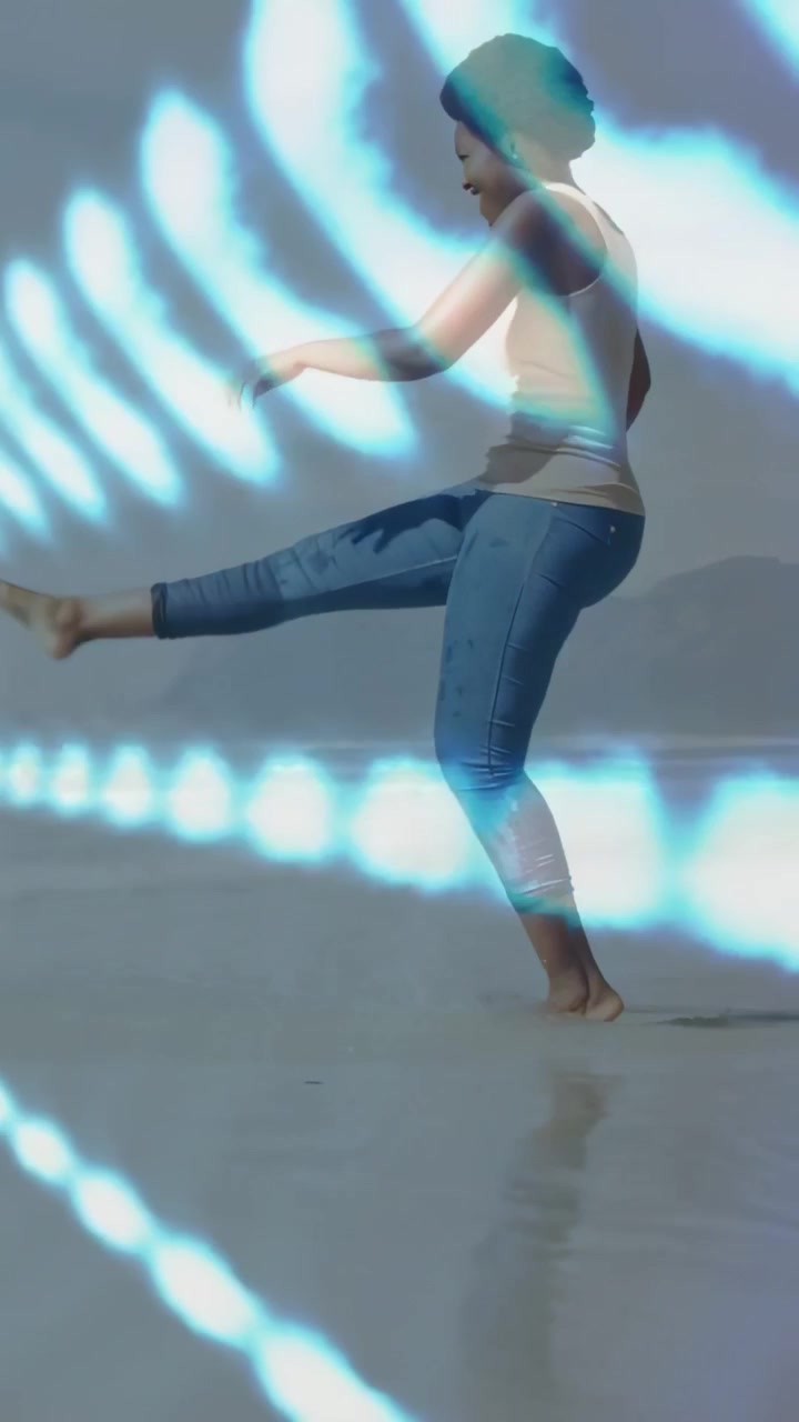 Vídeo vertical: Mulher andando na areia, com um hexágono neon de RA e uma onda passando por ela, iniciando a reprodução e depois saindo