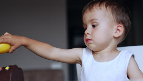 sweet caucasian kid focused on game. lovely baby boy plays with a toy bird. close up.