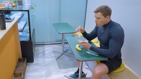 sportsman eating healthy fresh salad after workout inside cafe