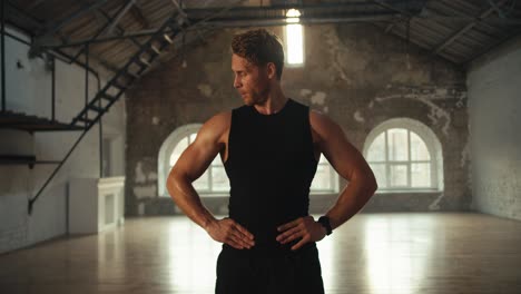 Portrait-of-a-male-athlete-in-a-black-sports-summer-uniform-who-raises-his-arms-up-and-shows-his-arm-muscles