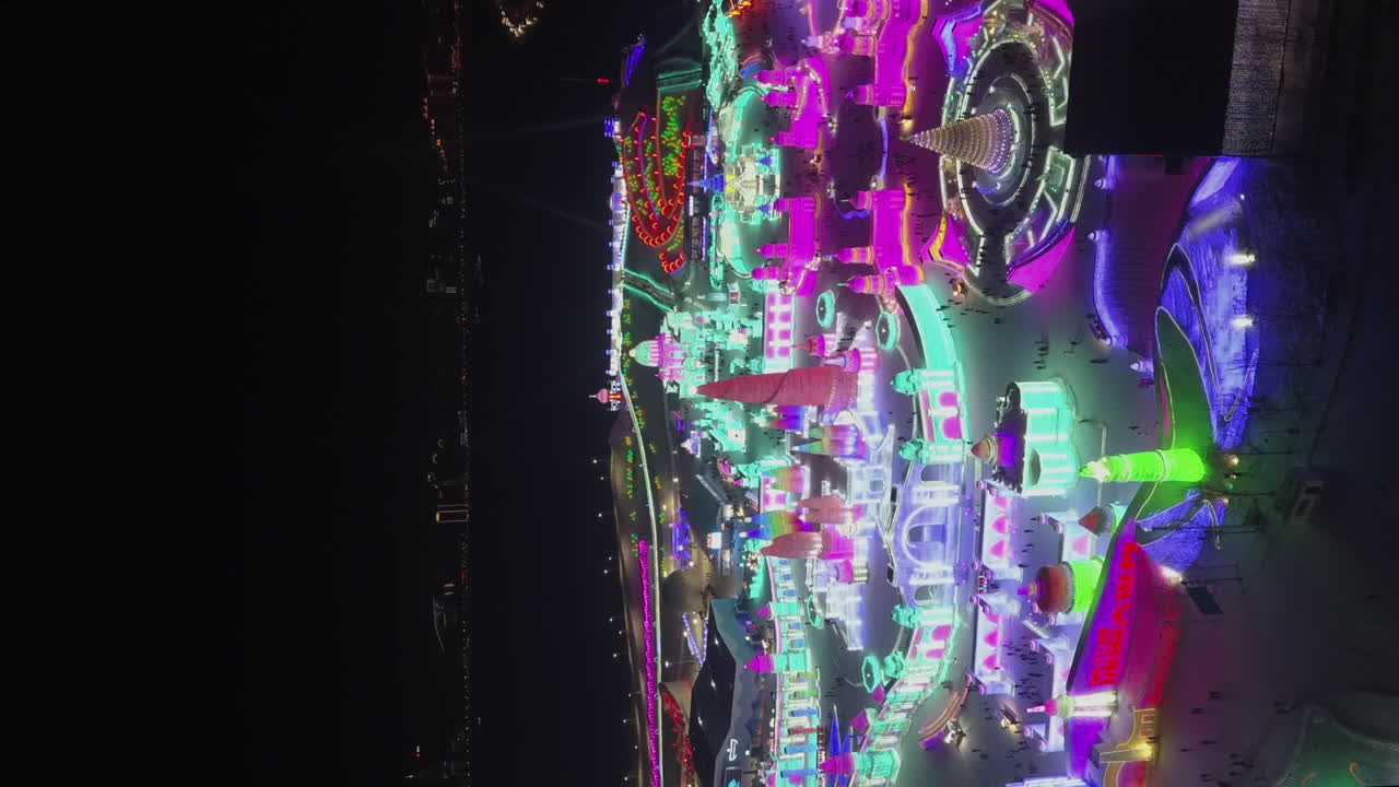 formato vertical: sobrevuelo aéreo nocturno de luces de colores del festival de hielo