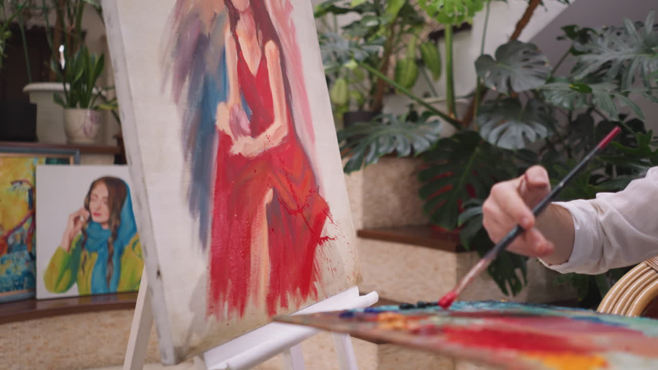 un hombre salpica pintura en el lienzo con un pincel. un artista profesional demuestra su capacidad para crear obras maestras visualmente atractivas y seductoras en un estudio de arte