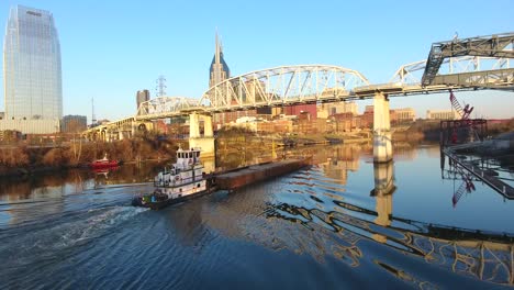 4k aerial nashville tennessee skyline tug boat going under bridge city urban roads