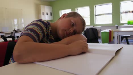 boy with his head on desk in the class