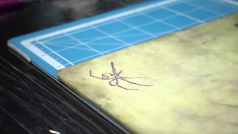 a tattoo artist printing the design of a spider on synthetic skin