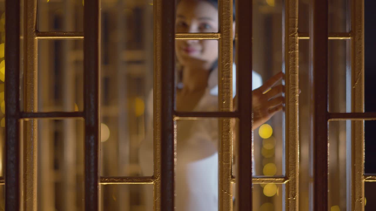 una mujer joven deslumbrante al otro lado de la puerta de vidrio se ve esquiva y burlona mientras sonríe