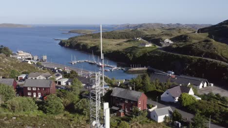 Drone-shot-of-the-village-of-Tarbert-with-a-radio-tower-passing-by-in-the-foreground
