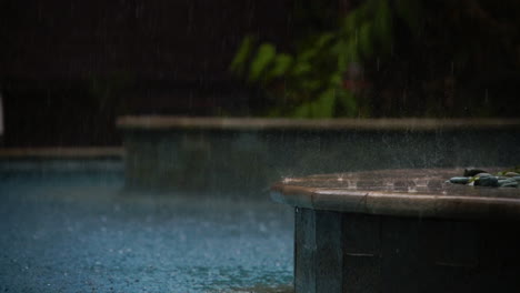 slow motion footage featuring water droplets splashing on a ledge next to a pool in the rain during a storm