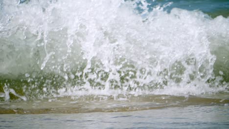 white, foamy waves rushing in and splashing at the sandy beachfront of a popular tourist destination in chonburi province in thailand