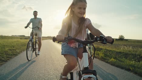 Family-of-four-caucasian-people-riding-bikes-on-village-road.